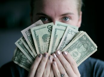 person holding fan of U.S. dollars banknote