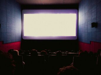 a large screen in a dark room with people watching it